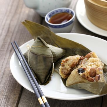 Traditional Chinese sticky rice dumplings wrapped in bamboo leaves with tea and chopsticks.