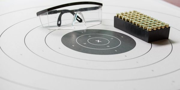 Shooting target with safety glasses and a box of bullets.