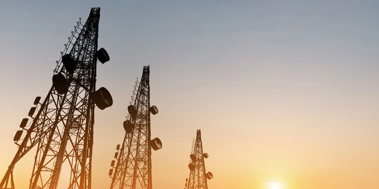 Tall communication towers silhouetted against a sunset sky.