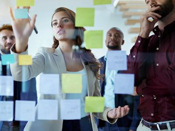 Team brainstorming ideas on sticky notes in an office meeting.