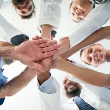 Medical professionals joining hands in a team huddle, symbolizing unity and collaboration.
