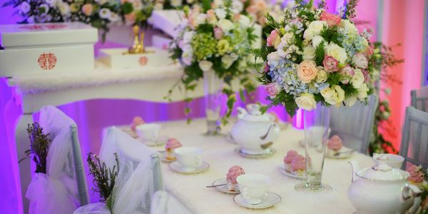 Elegant tea party setup with floral arrangements and delicate porcelain.