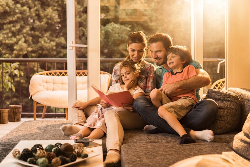 Young happy family relaxing on sofa in the living room and reading a book.