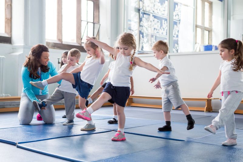 Nursery teacher helping one of her students during a physical education lesson.