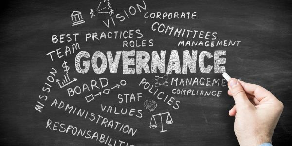 Hand writing governance-related terms on a chalkboard.