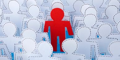 A red paper figure stands out among white figures.