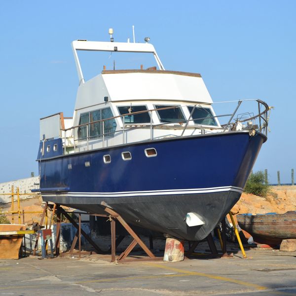 A blue and white boat on dry dock with other boats nearby.
