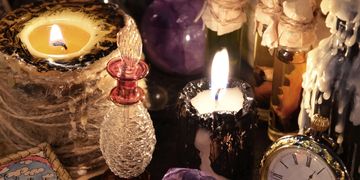 A cozy scene with candles, a vintage clock, and decorative glass bottles.