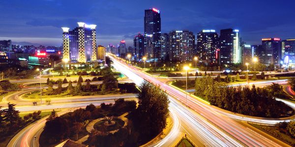 City highway interchange with illuminated skyscrapers at night.