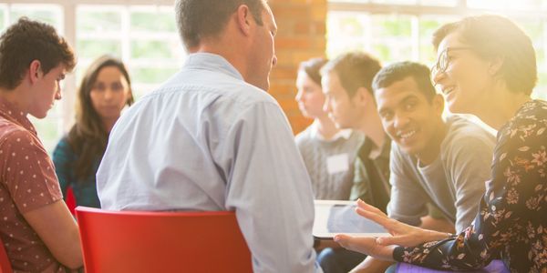 A group of diverse people engaged in a lively discussion in a bright room.