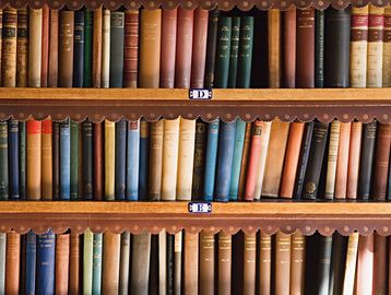 Rows of vintage hardcover books on wooden shelves.