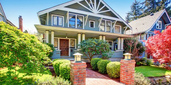 Charming craftsman-style house with a brick pathway and lush garden.