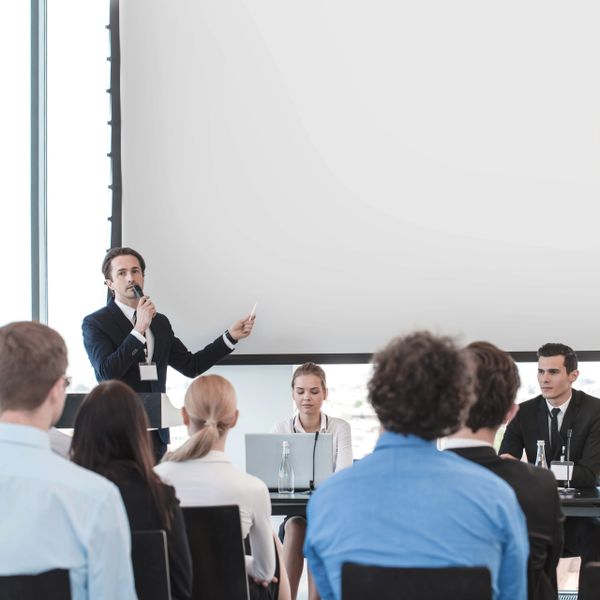 A man giving a presentation to an audience in a conference room.
