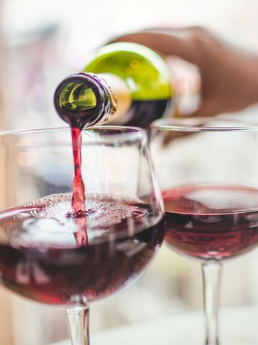 Red wine being poured into a glass from a green bottle.