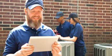 Technicians working outside with a tablet and HVAC units.