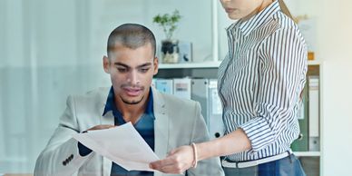 Two colleagues reviewing documents together in a modern office.