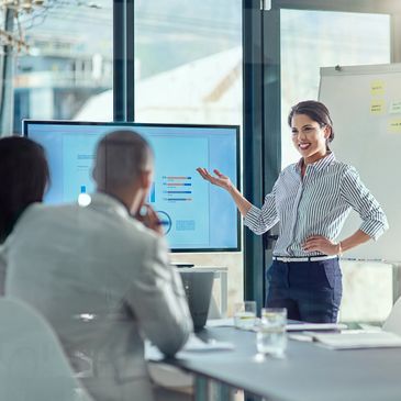 A woman presents data on a screen to colleagues in a modern office.