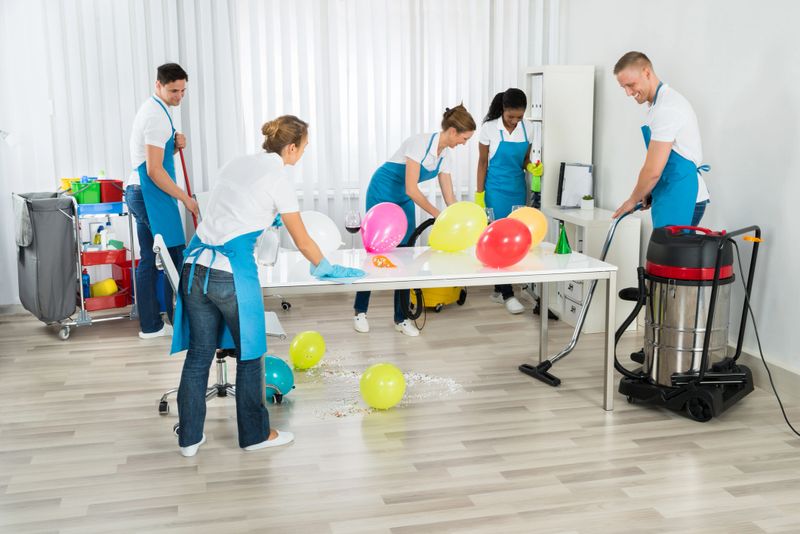 Group Of Male And Female Janitors Cleaning The Office After Party