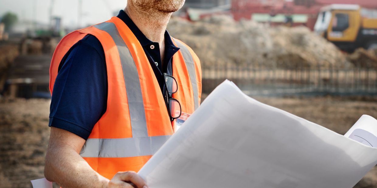 Construction worker reviewing plans on site.