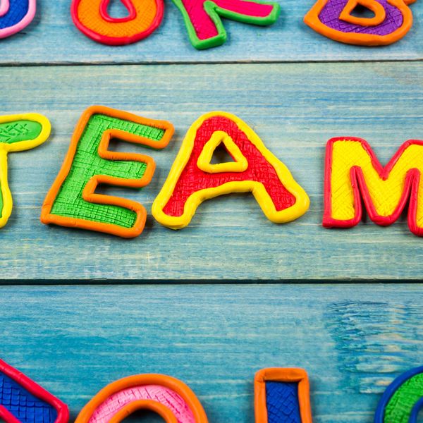 Colorful letters on a wooden surface spell out 'TEAM'.