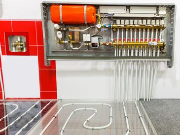 Underfloor heating system with manifold and pipes installed beneath the floor.