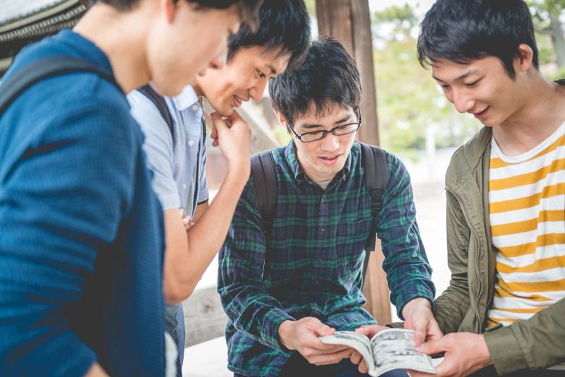 Four male Japanese students looking at Manga, having fun in the park of The Chion-ji Temple, Kyoto, Japan, Asia.  Copy space. Nikon D800, full frame, XXXL. iStockalypse Kyoto 2016.