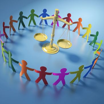 Colorful paper people hold hands around golden scales of justice on blue.