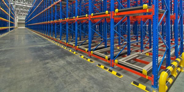 Empty industrial warehouse racks with blue and orange metal frames.