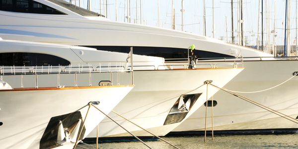 Two white yachts docked side by side in the marina.