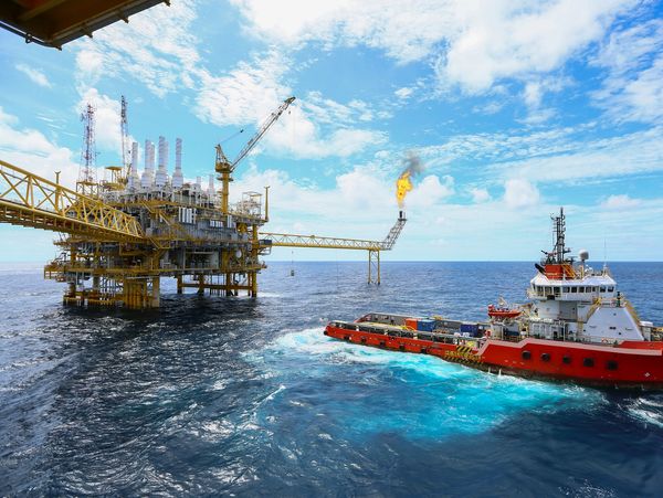 Offshore oil rig with service vessel nearby.