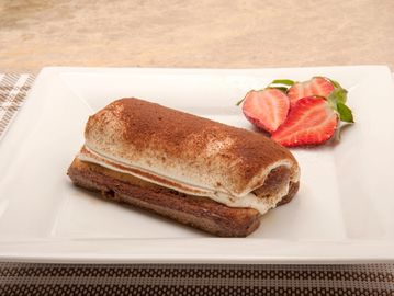 A tiramisu dessert with cocoa powder and sliced strawberries on a white plate.