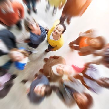 Focused woman in yellow among a blurred crowd looking up.
