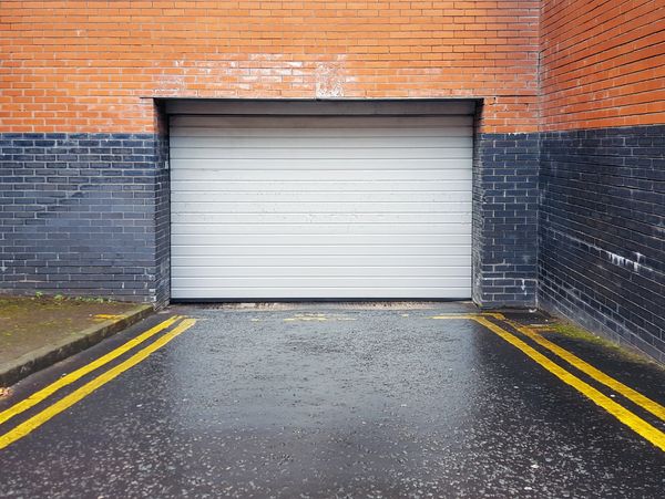Closed white garage door framed by orange and black brick walls.