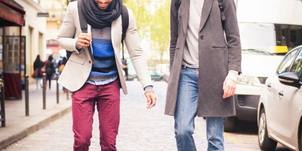 Two men walking and talking on a city street, dressed in stylish casual autumn clothing.