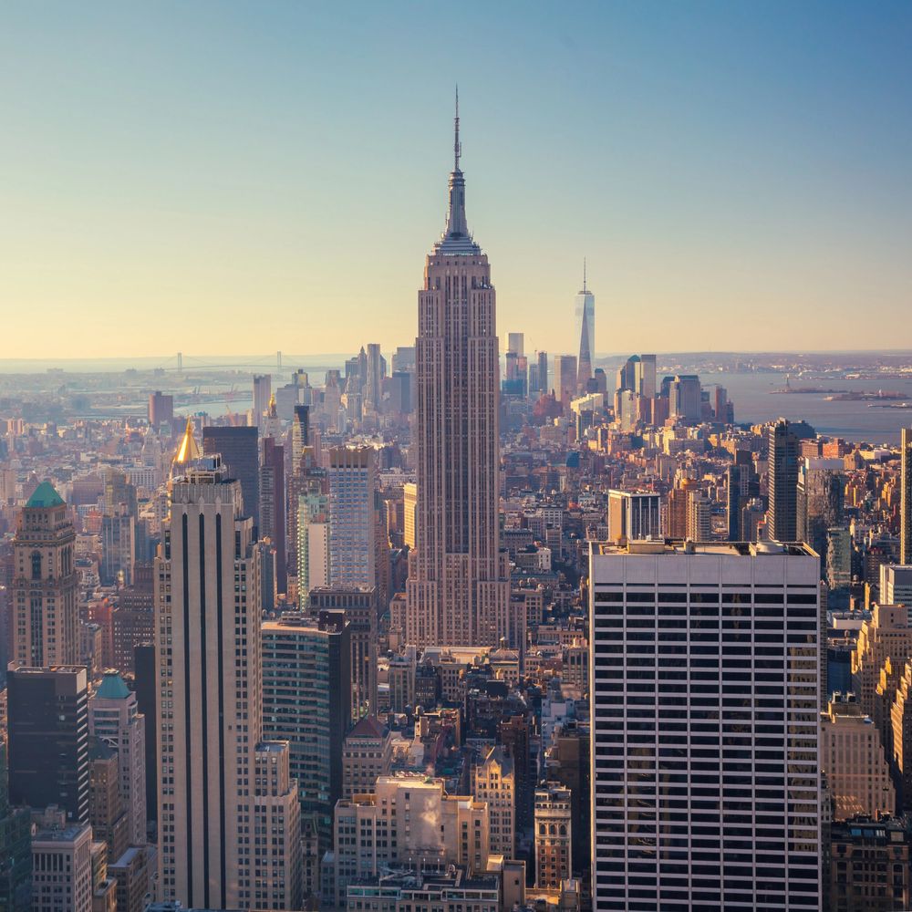 Empire State Building towering over New York City skyline at sunset.