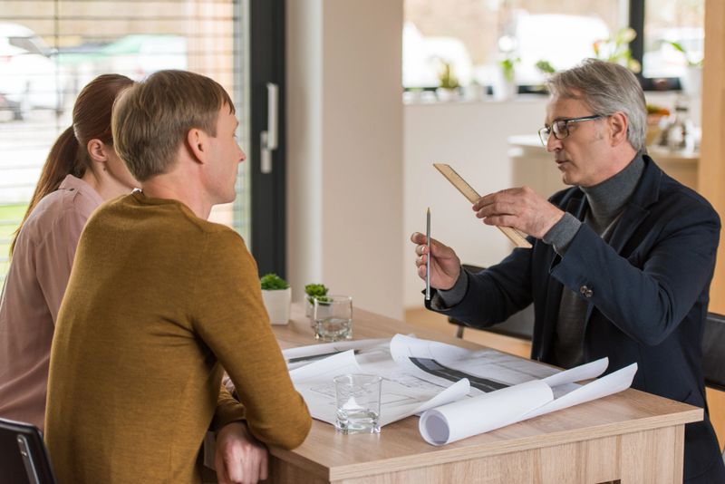 Consultant gesturing while explaining to mid adult couple at home.