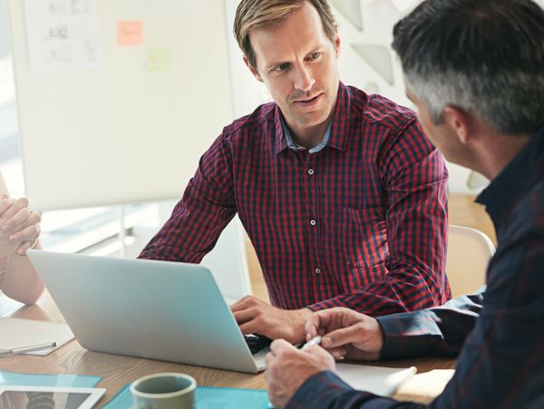 Two men in a business meeting discussing work on a laptop.