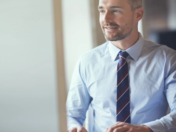 Smiling businessman in a light blue shirt and striped tie at work.