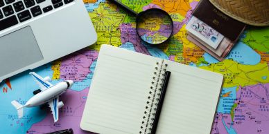 Travel planning setup with map, notebook, and laptop.