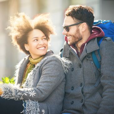 Couple smiling warmly at each other outdoors in winter.