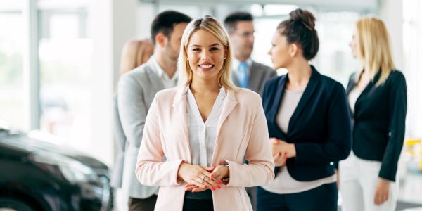 Confident businesswoman smiling with team in background.