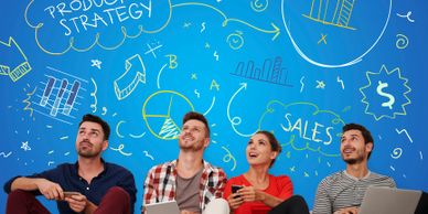 Four people sitting on the floor with digital devices under a blue wall with business strategy doodles.