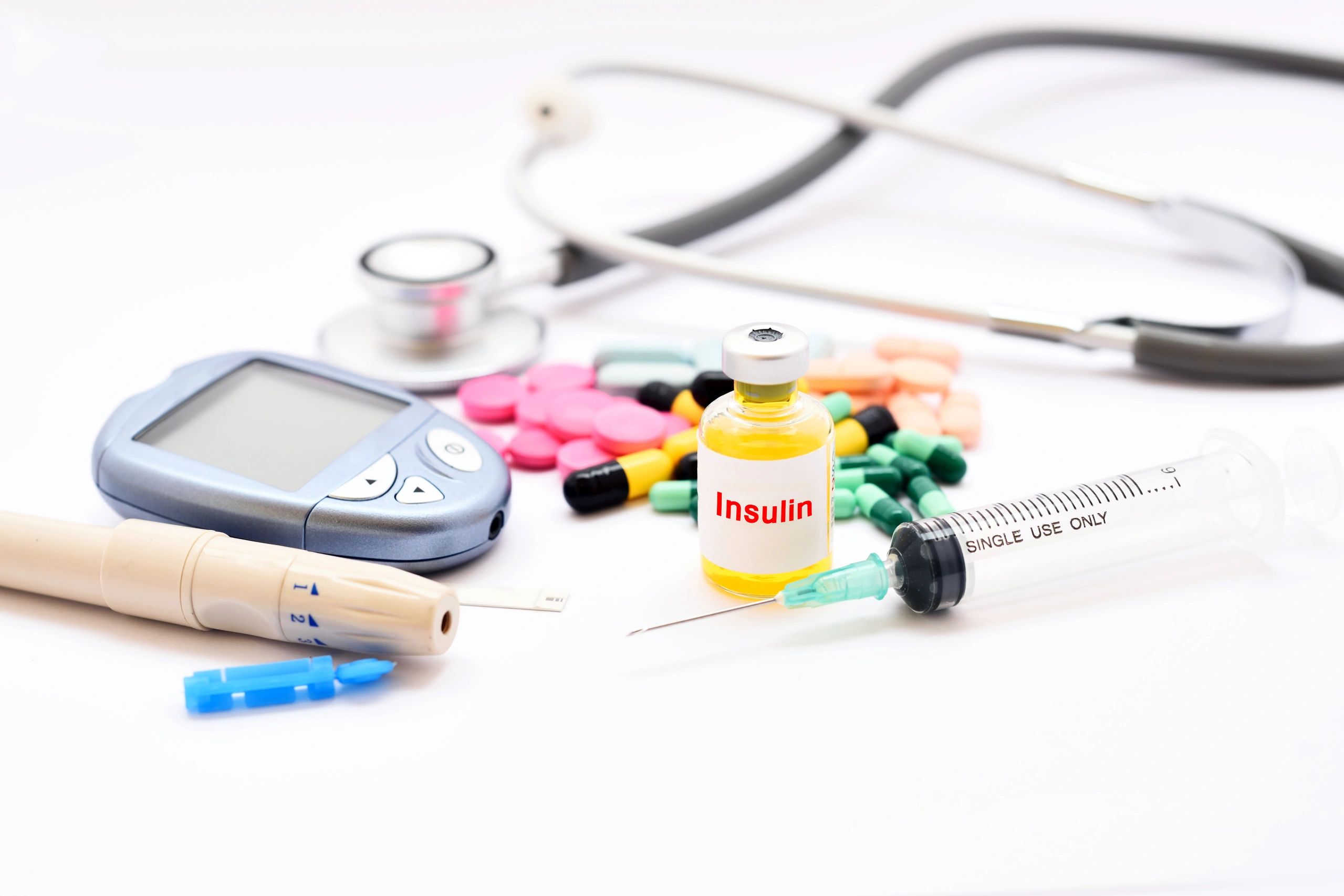 Insulin vial, syringe, glucose meter, and pills for diabetes management.