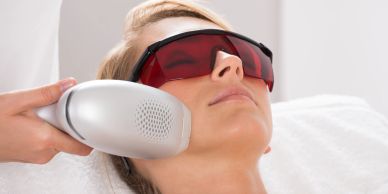 Woman undergoing laser skin treatment with protective eyewear.