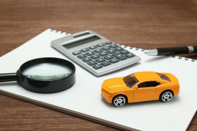 Magnifying glass, calculator, toy car, and pen on notebook.