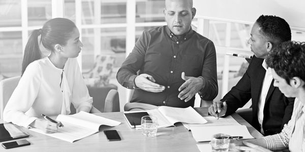 Four professionals engaged in a discussion around a table with documents.
