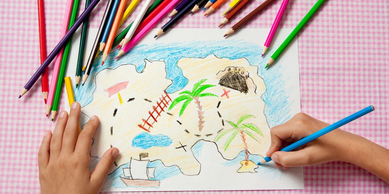 Child drawing a colorful treasure map with colored pencils.