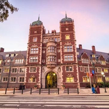 Historic building with twin towers and clock at sunset.