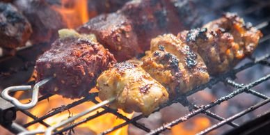 Grilled meat skewers cooking over an open flame.