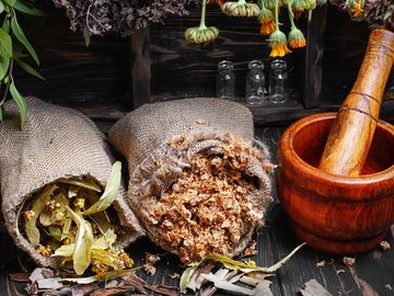 Burlap sacks with dried herbs and a wooden mortar and pestle.